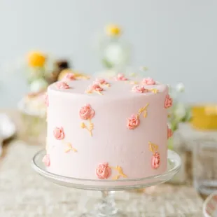 a pink cake on a glass cake stand