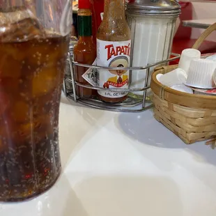 a glass of soda and a basket of condiments