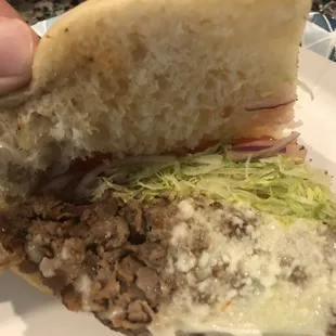 a hand holding a half eaten sandwich