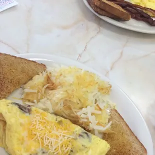 Cheese bacon eggs omelette with hash browns and bread. The wife had pancakes eggs and bacon