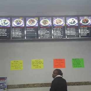 a man standing in front of a menu board