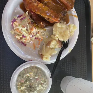 Bbq ribs in sauce with Cole slaw, roasted red potatoes in butter, and pea salad