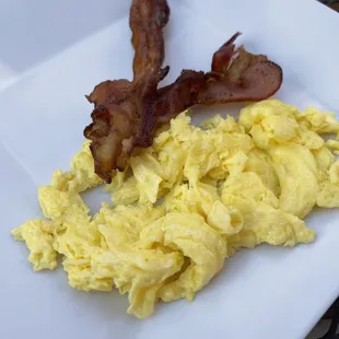 Scrambled eggs with two strips of bacon