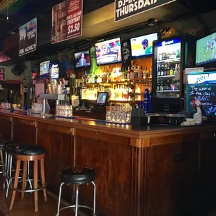 a bar with stools and televisions