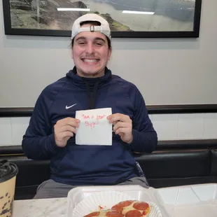 My bf with his pizza bagel and the note.