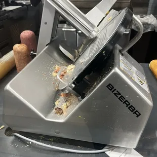 A very filthy meat cutter with meat sitting there that looks like it's been there all day
