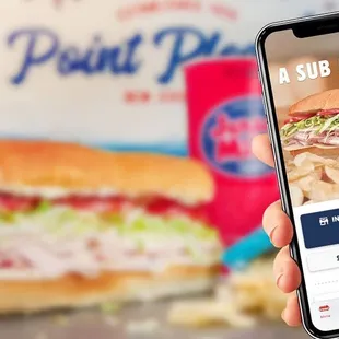 a hand holding a phone with a sandwich on the screen