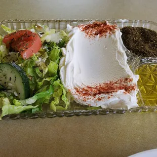 Labaneh- smooth creamy dip made of goat milk with lemony taste, side of olive oil &amp;spices  . Includes a side salad and pita bread