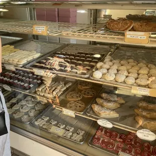 a woman standing in front of a display case of baked goods