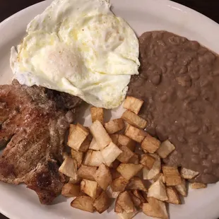 juicy porkchop with eggs, potatoes and beans