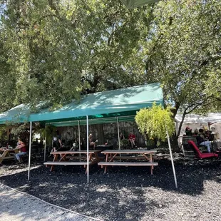 people sitting at picnic tables under a canopy
