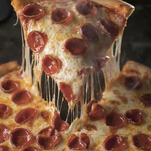 a slice of pepperoni pizza being lifted by a spatula