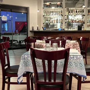 a dining room with a bar in the background