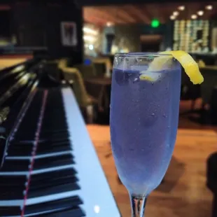 a glass of blue liquid with a lemon wedge