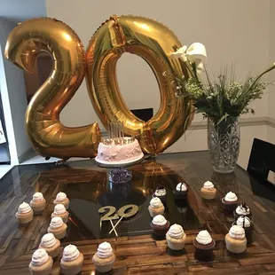 a table with cupcakes and balloons