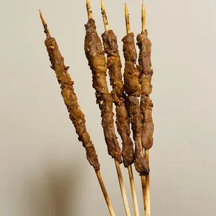 a hand holding a bunch of skewered meat