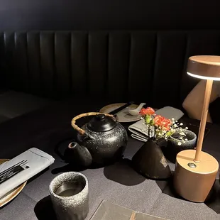 a table with teapots, a lamp, and a book
