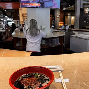 a bowl of noodles and chopsticks on a counter