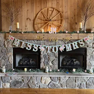 a stone fireplace with a garland of flowers and candles
