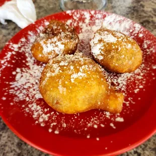 a plate of donuts covered in powdered sugar