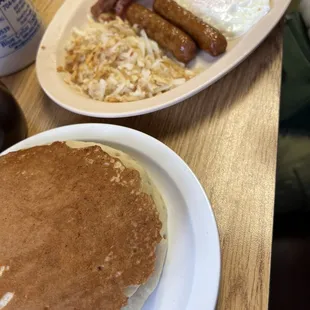 a plate of pancakes, eggs, sausages, and hash browns