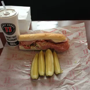 a sandwich with pickles and a drink