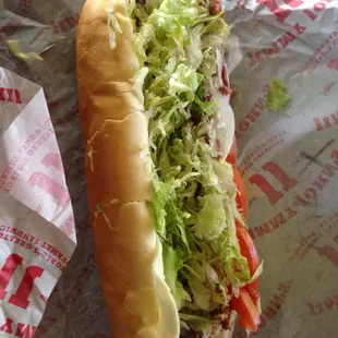a hot dog with lettuce and tomatoes