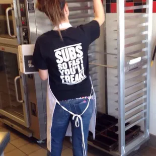 Snapped a worker walking from the back with bread before placing them on the rack.