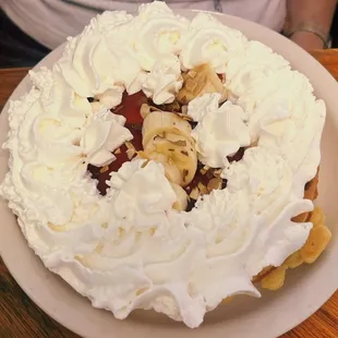 Belgian waffle with strawberries bananas and whipped cream.