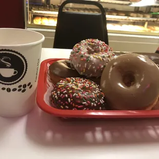 a tray of doughnuts and a cup of coffee