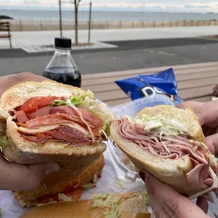 two hands holding sandwiches
