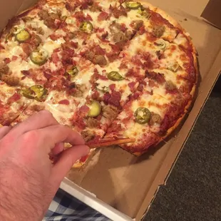 a hand holding a slice of pizza