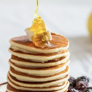 a stack of pancakes with syrup and berries
