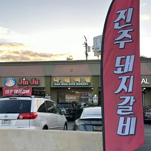 Flag banner on the sidewalk of Western ave. that reads &quot;Jinju Pork Ribs&quot; in korean