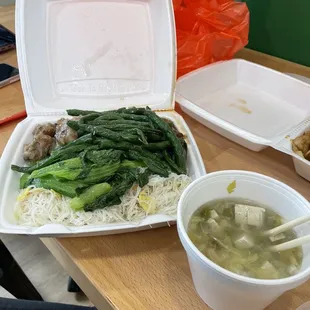 a take out container of soup and vegetables