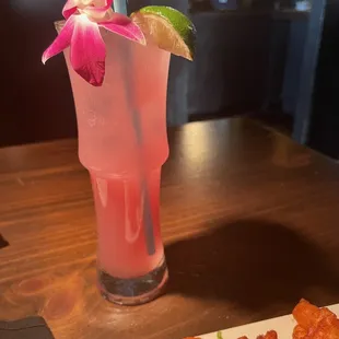 a pink drink with a flower garnish