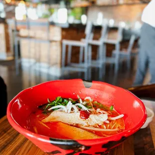 a red bowl of ramen with noodles and vegetables