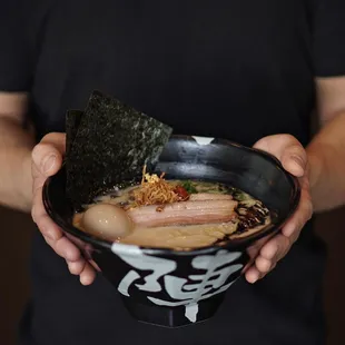 a man holding a bowl of ramen