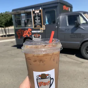a hand holding a cup of iced coffee