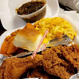 a plate of fried chicken, macaroni and cheese, and a roll