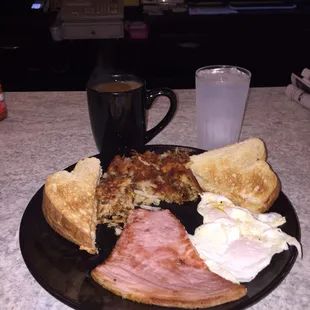Over easy eggs, ham, toast and hash browns with coffee