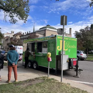 a green food truck parked on the side of the road