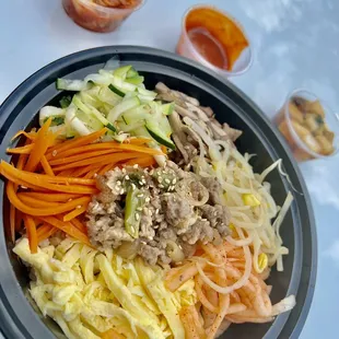 Spicy beef Bibimbap with bean sprouts, carrots, radish, onions, eggs, cucumbers, and mushrooms.