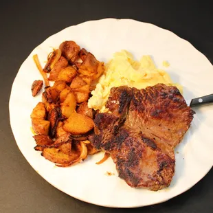 a plate of meat, eggs, and potatoes