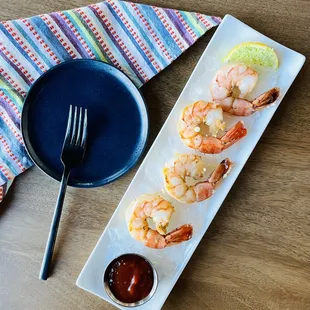 a plate of shrimp with a side of ketchup