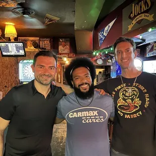 three men standing in a bar