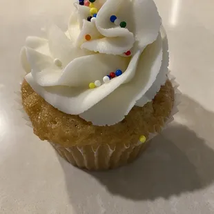 a cupcake with white frosting and sprinkles