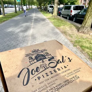 a hand holding a pizza box