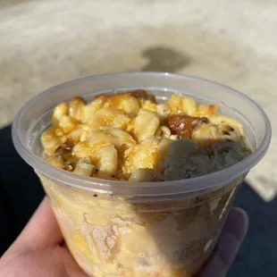 a hand holding a cup of macaroni and cheese