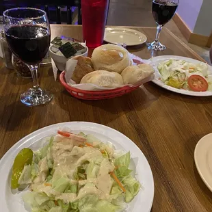 Salads served with fresh bread knots and a delightful bouquet of Cabernet wine to accompany.